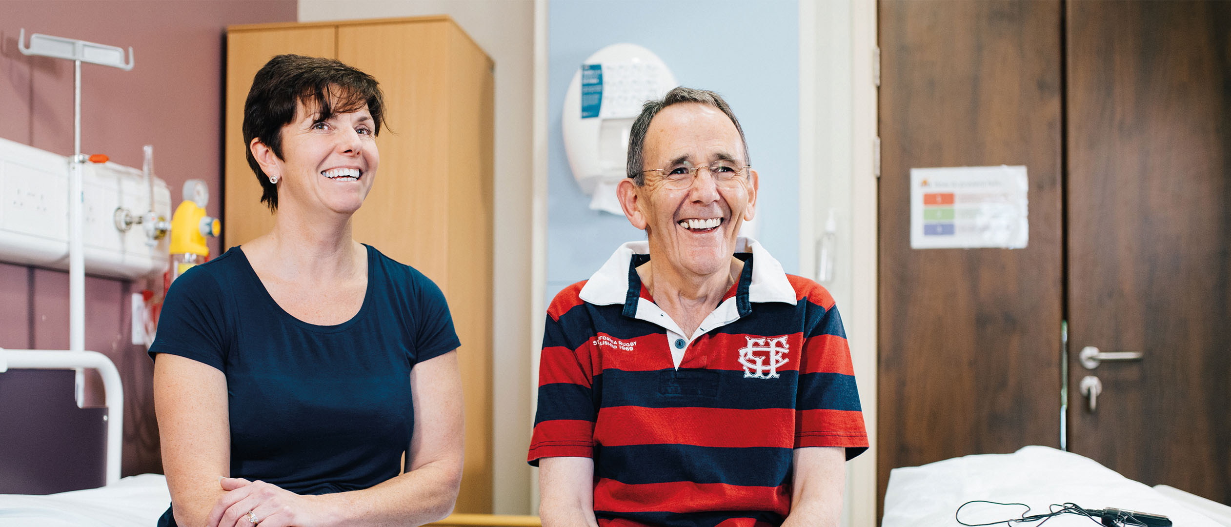 a woman and a man sitting on a hospital bed